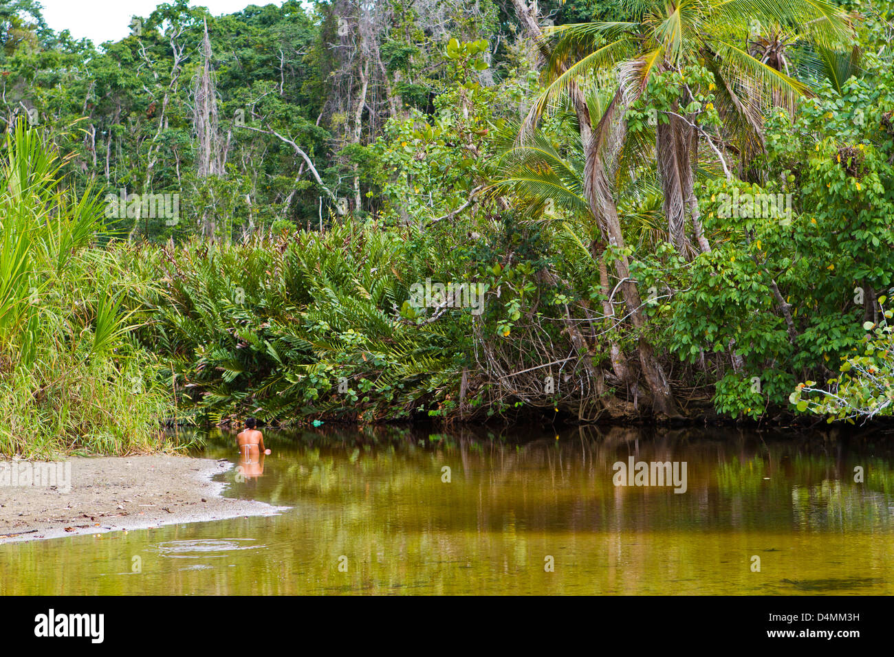 Young girl resting in river with lush vegetation Stock Photo