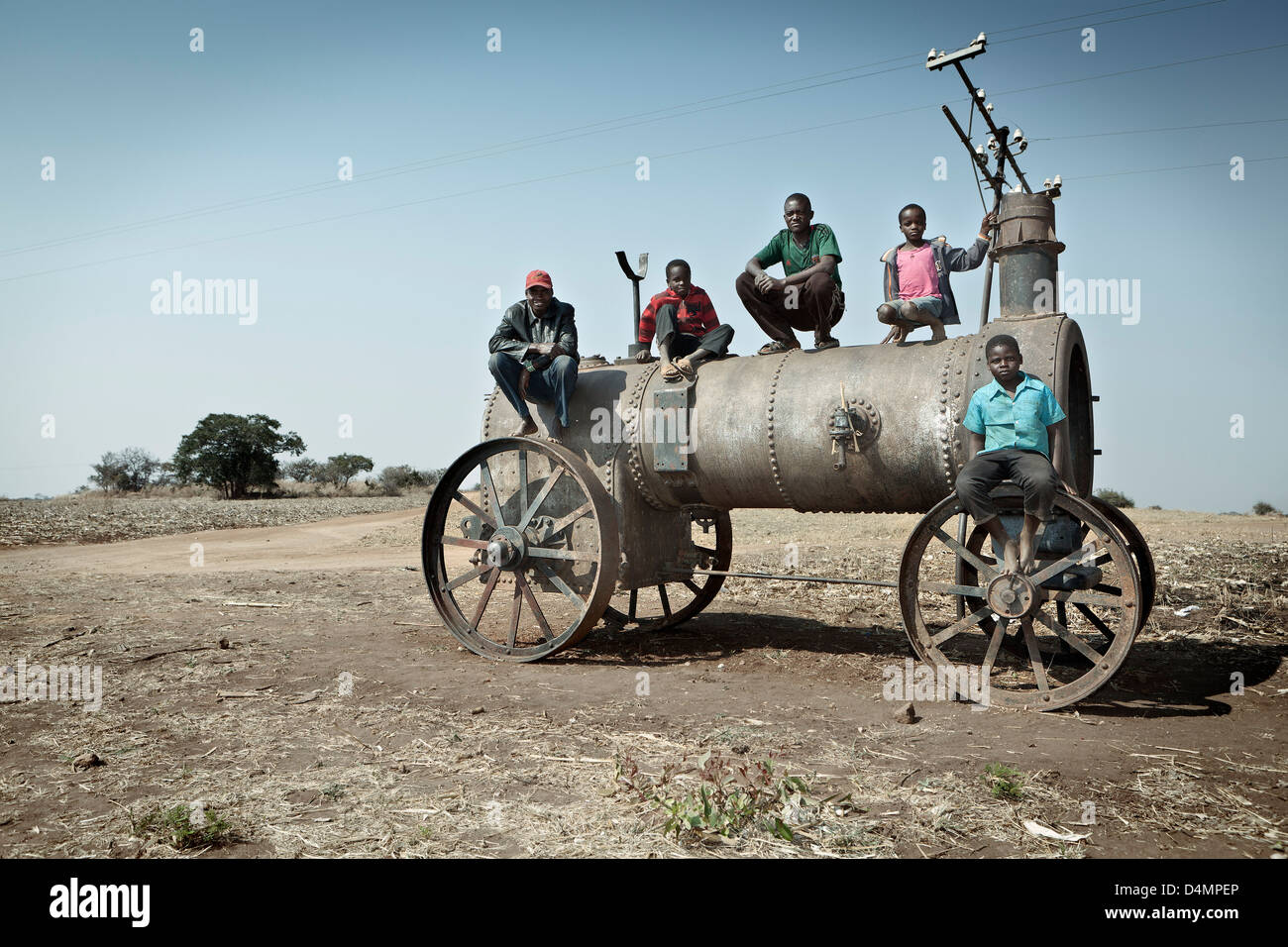 Five boys sitting on an old disused steam train on the edge of a farming plot on the in Harare , Zimbabwe. Stock Photo