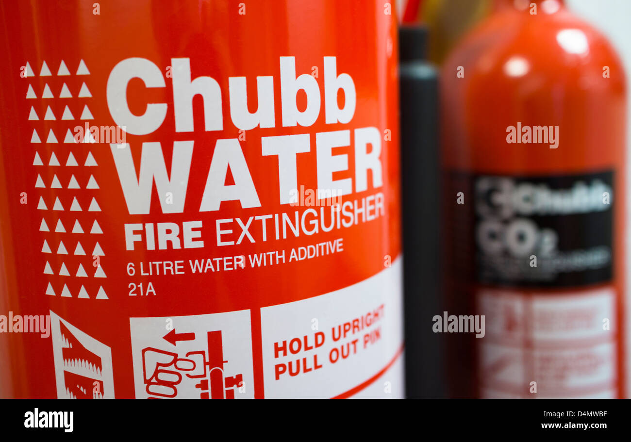 Two Chubb Fire extinguishers mounted on a wall, one water with Additive 21A and the other CO2. Stock Photo