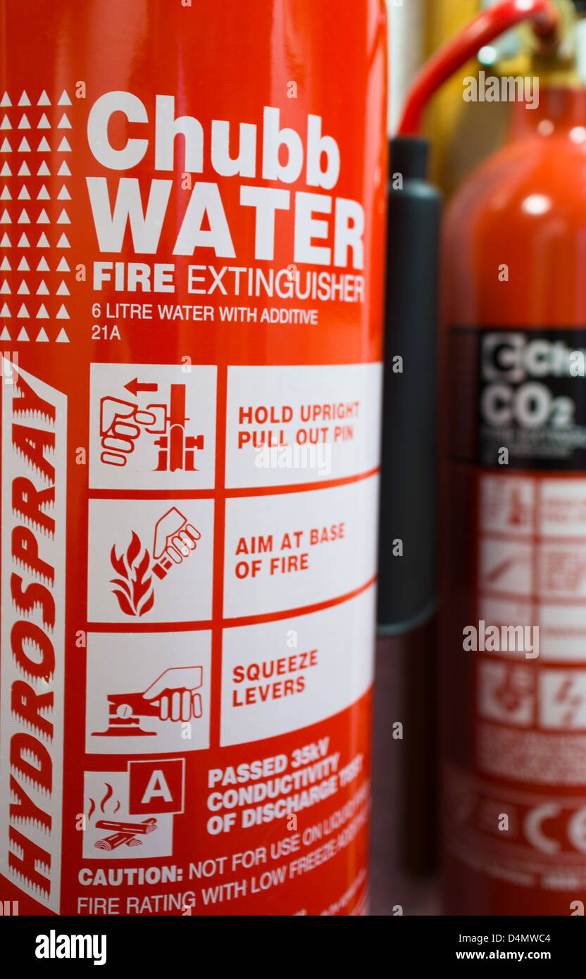 Two Chubb Fire extinguishers mounted on a wall, one water with Additive 21A and the other CO2. Stock Photo
