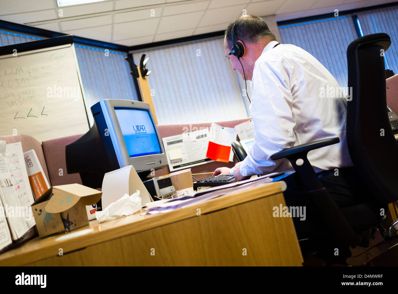 A office worker on the telephone with a headset at his desk. Stock Photo