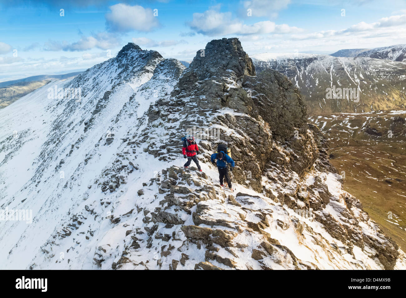 Two walkers climbing over Striding Edge towards Helvellyn in the Lake District. Stock Photo
