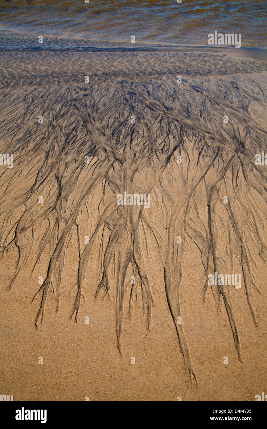 Sand Patterns on a beach beside a stream at low tide. Stock Photo