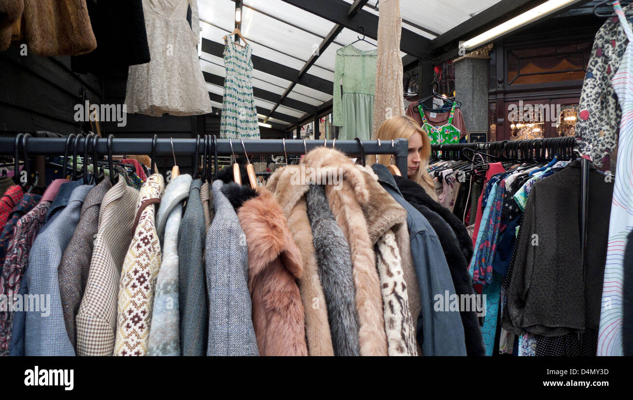Woman browsing antique clothing store stall with winter and fur coats on rail in Camden Passage London N1 UK   KATHY DEWITT Stock Photo