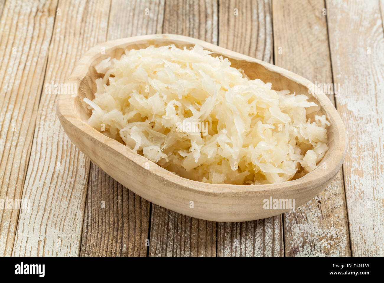sauerkraut in a rustic wooden bowl against white painted wooden background Stock Photo