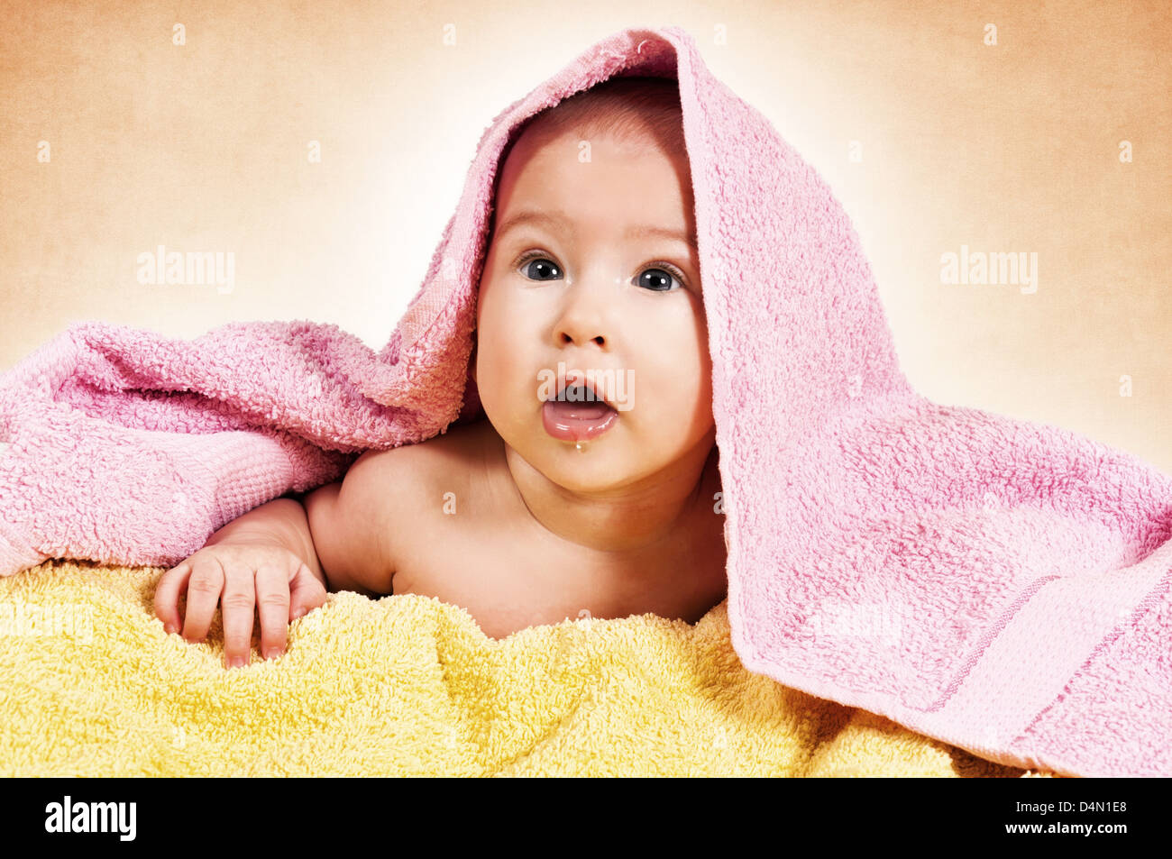 Baby girl under the towels on orange background Stock Photo Alamy