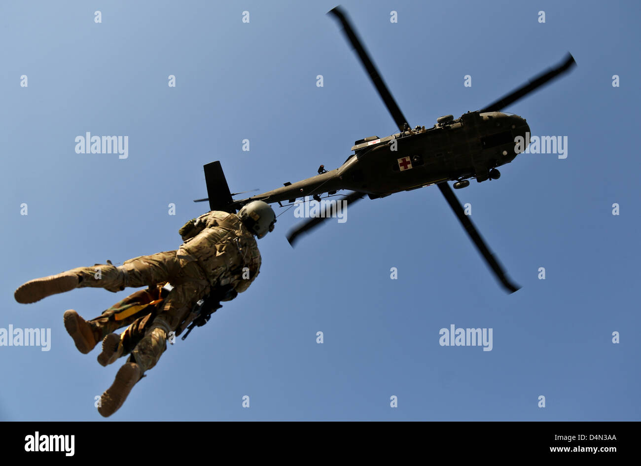A US Army flight medic and an Afghan National Army commando are hoisted to a US Army UH-60 Black Hawk helicopter during extraction training March 4, 2013 in Bihsud district, Nangarhar province, Afghanistan. ANA commandos and coalition forces conducted the training in preparation for possible casualty extractions during combat operations. Stock Photo