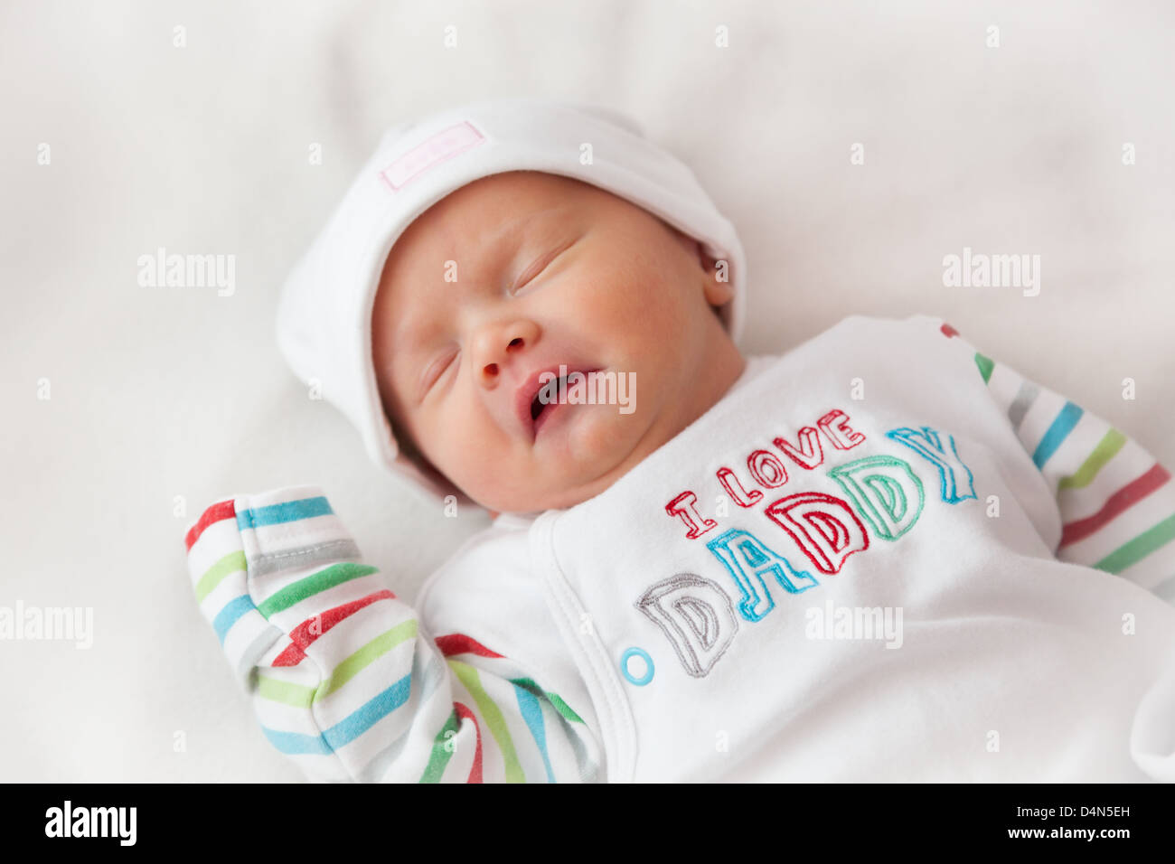 Sleeping baby girl (8 days old) taken in a very soft light (a light tent). Hat reads 'cute' and top reads 'I love Daddy'. Stock Photo
