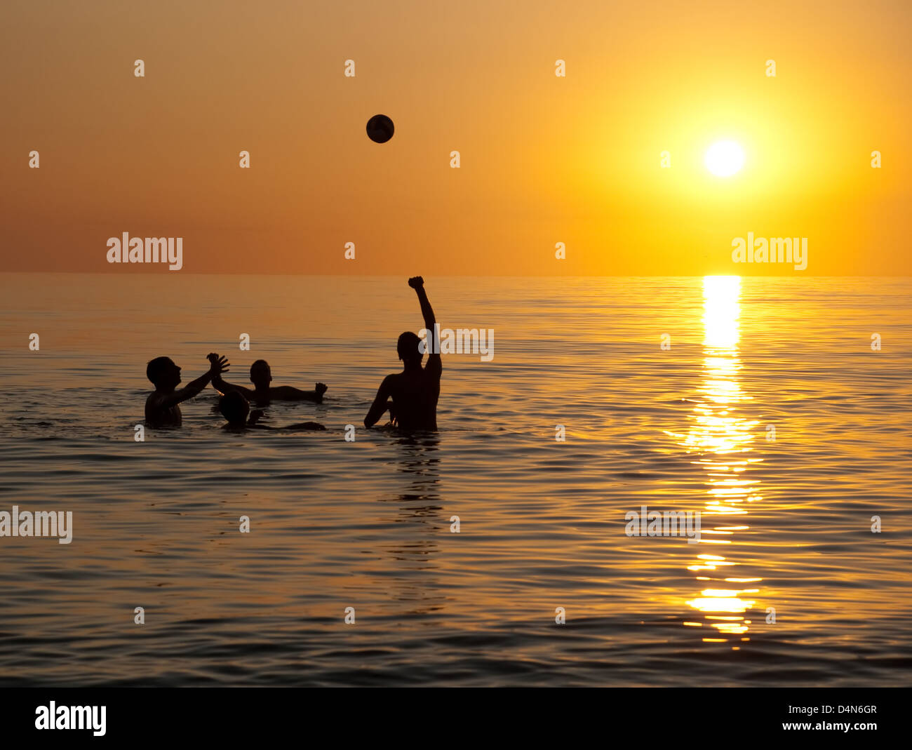 Young people playing in ocean at sunset Stock Photo