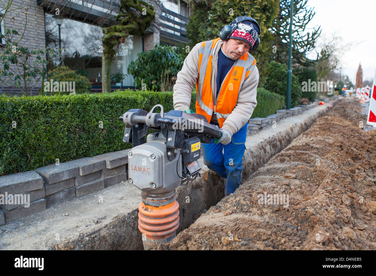 Polish migrant worker doing earthwork stomping ground with a Samac for the construction of a glass fiber network Stock Photo