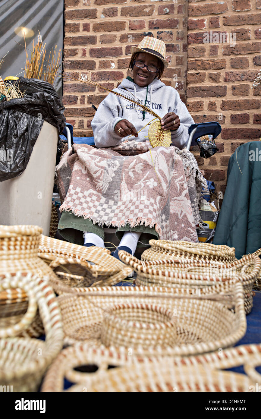 Gullah woman weaving sweetgrass baskets at the Historic Charleston City Market on Market Street in Charleston, SC. Stock Photo