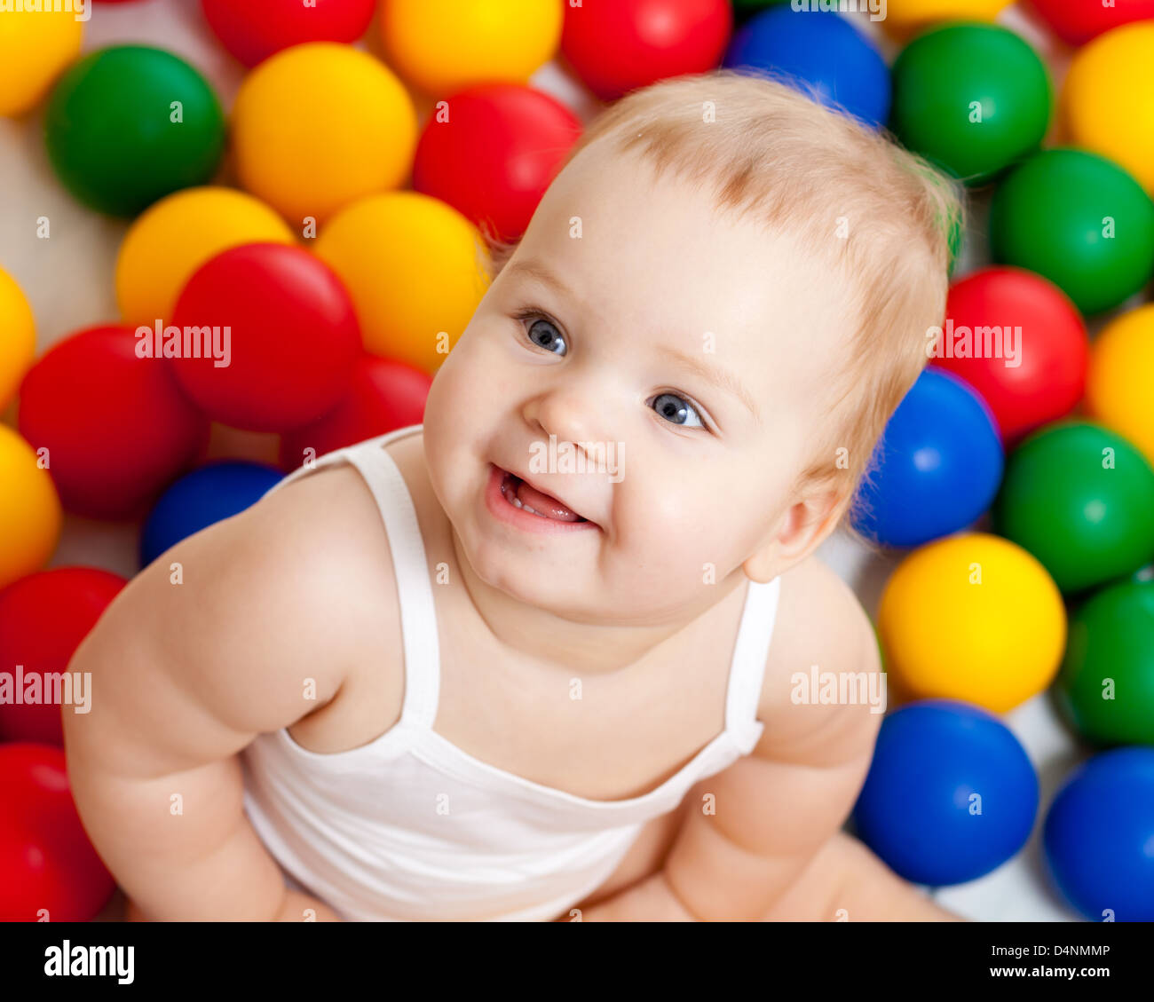 Portrait of a smiling infant sitting among colorful balls Stock Photo