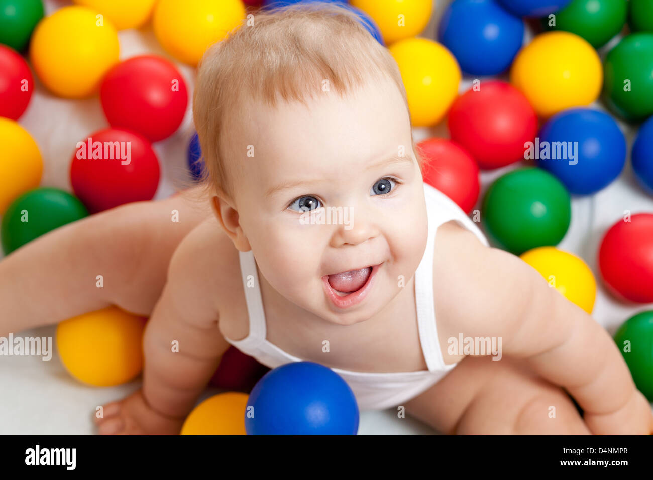 Portrait of a adorable infant sitting among colorful balls Stock Photo