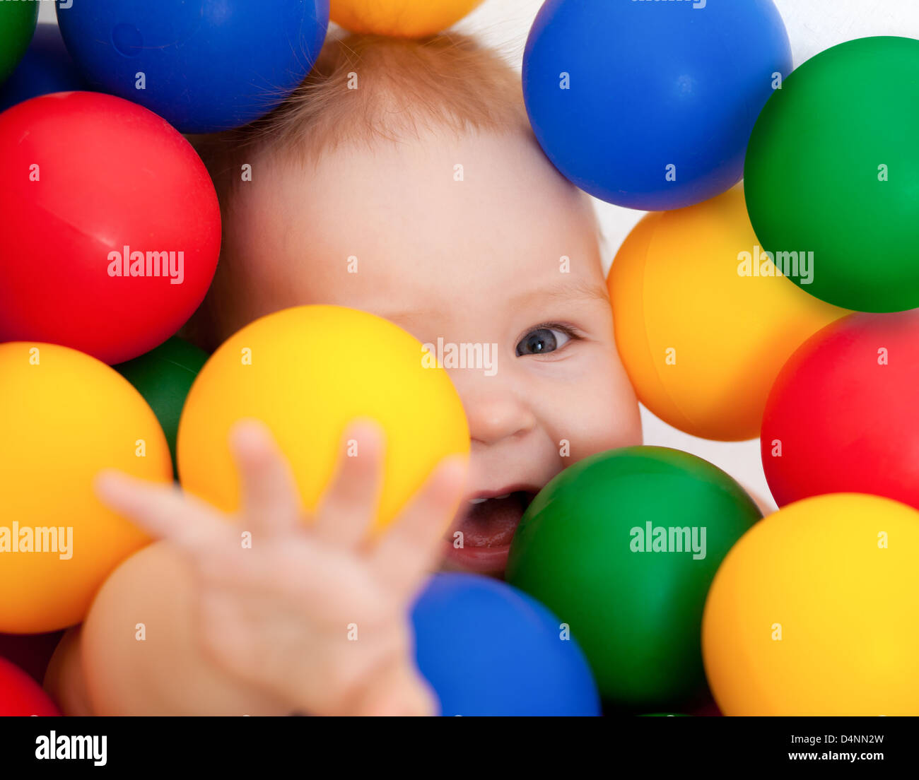 Portrait of a smiling infant lying among colorful balls Stock Photo