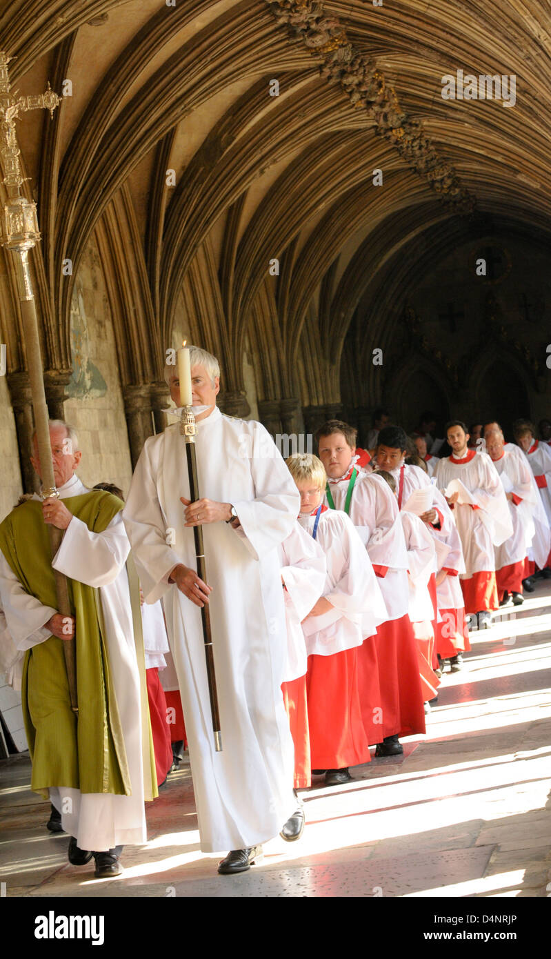 A line of choristers in red cassocks and white surplices follow a cross