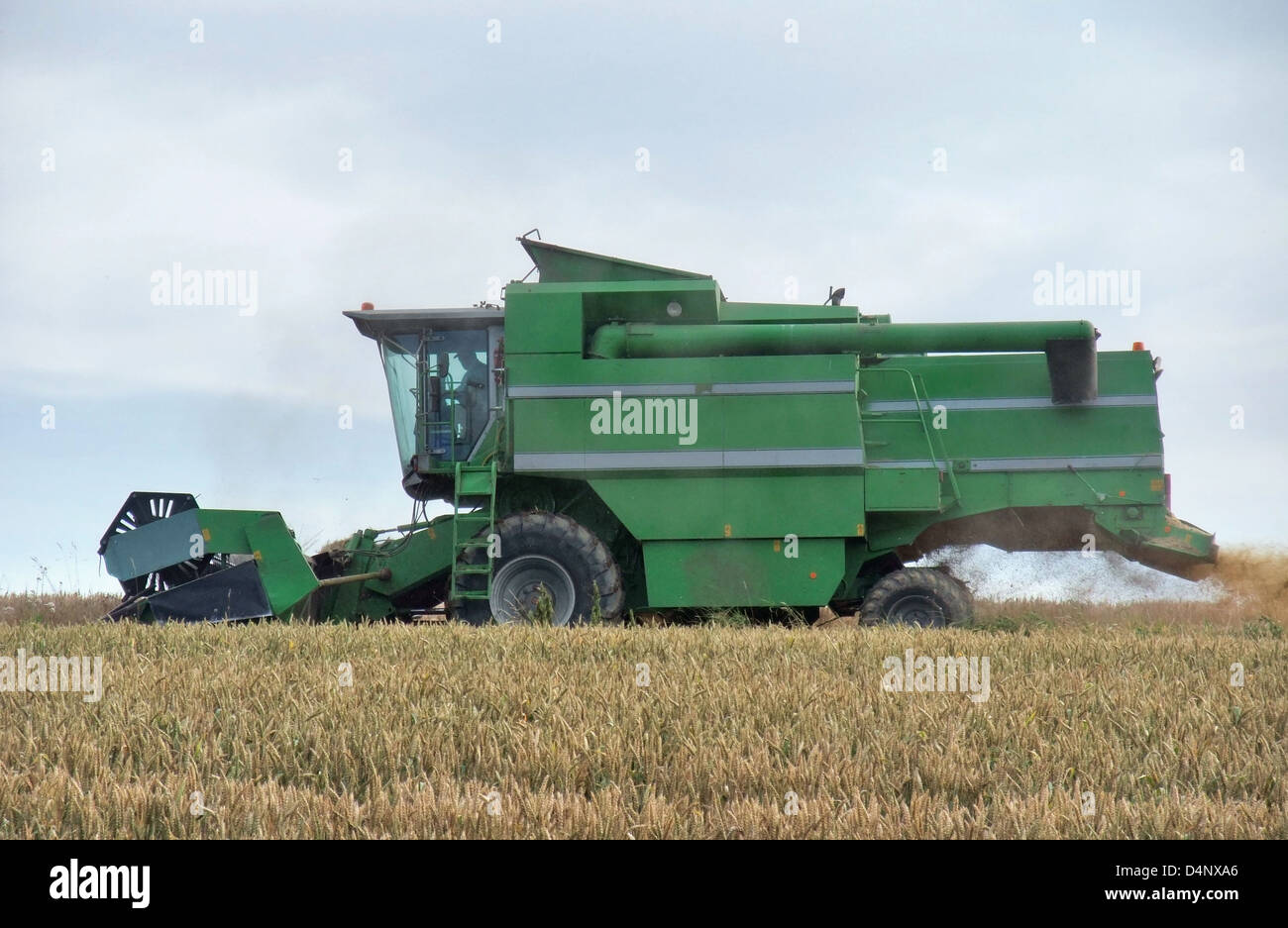 agricultural scenery showing a green harvester at the edge of a crop field while harvesting at summer time in Southern Germany Stock Photo