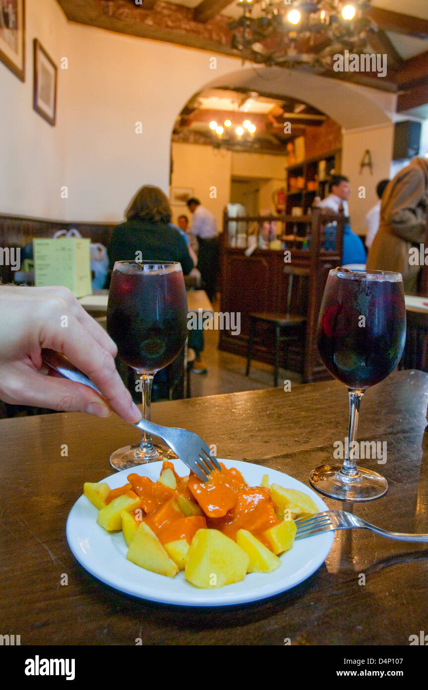 Man's hand having patatas bravas serving in a typical tavern. Madrid, Spain. Stock Photo