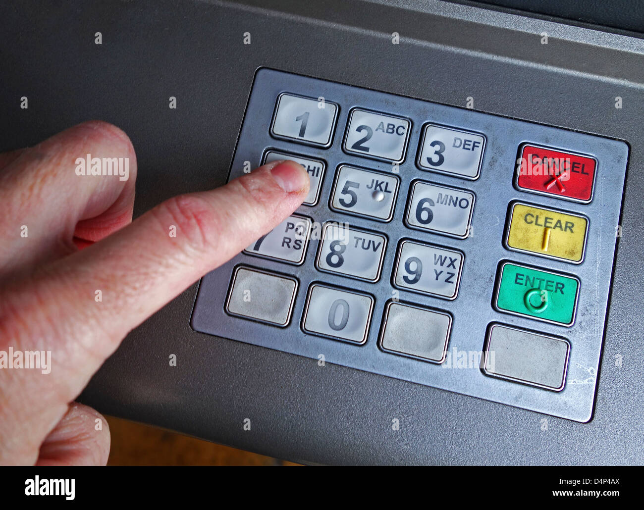 a finger pressing a number on a keypad at an ATM Stock Photo