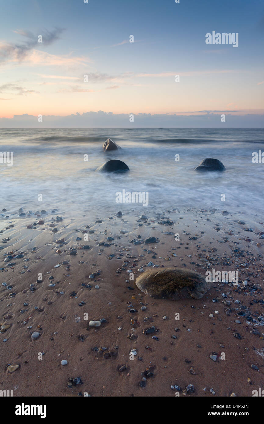 Waves wash over rocks on the beach at sunset at Smidstrup Strand in Denmark, August 2011 Stock Photo
