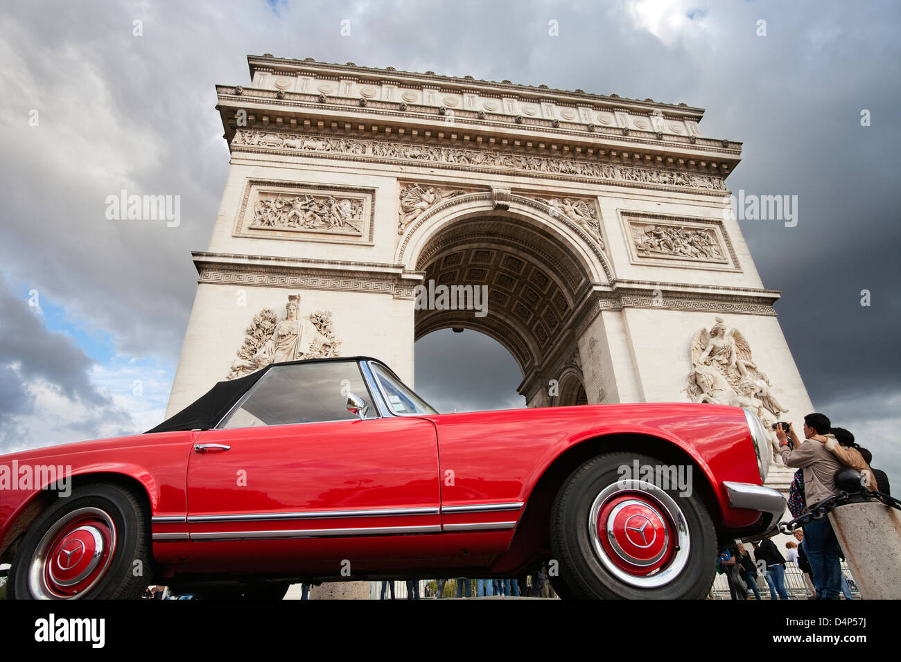 Japanese couple photographing the Arc de Triomphe in Paris; red Mercedes veteran car in front of  Arc de Triumph Stock Photo
