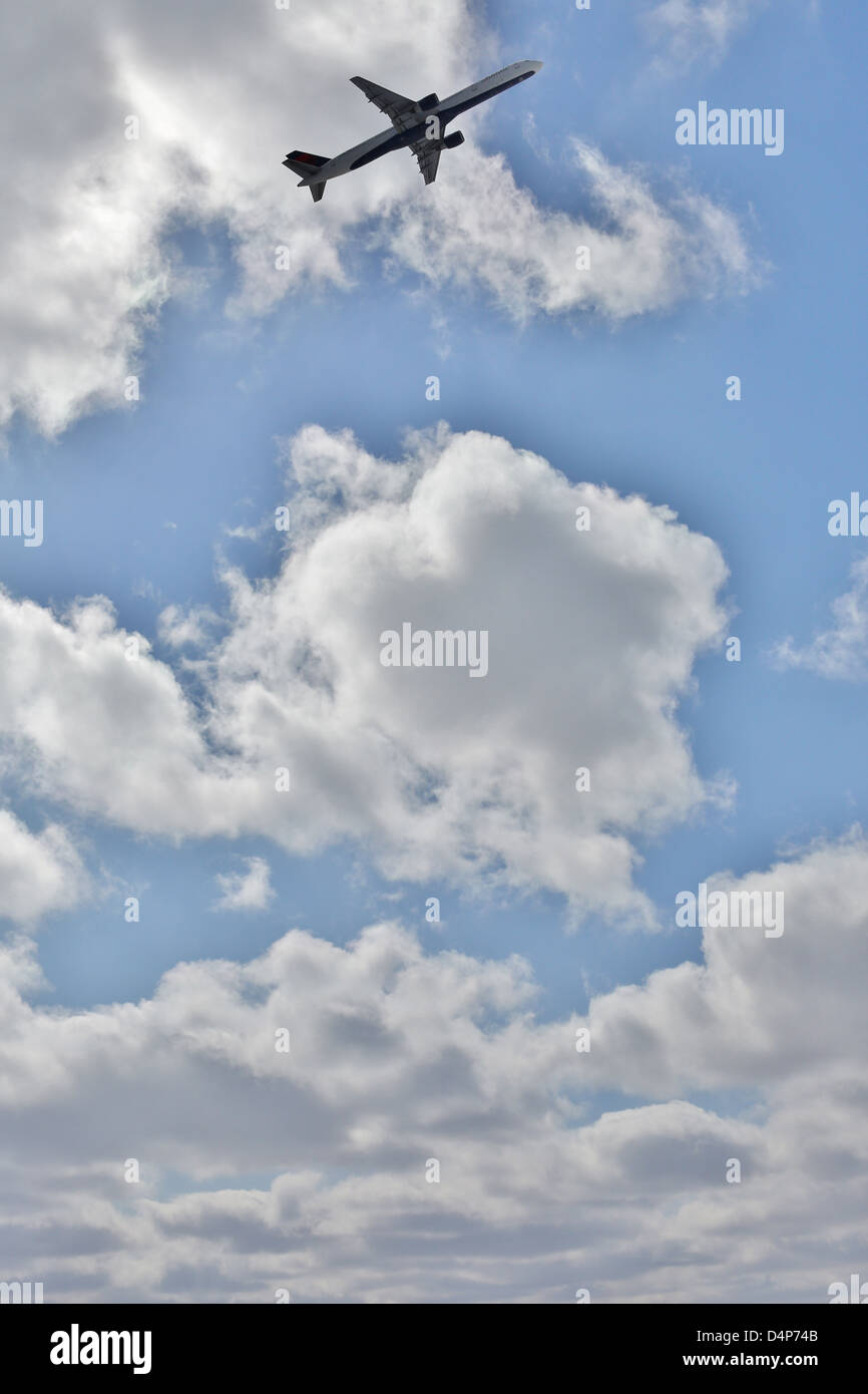 An airplane flying in clouds and blue sky Stock Photo - Alamy