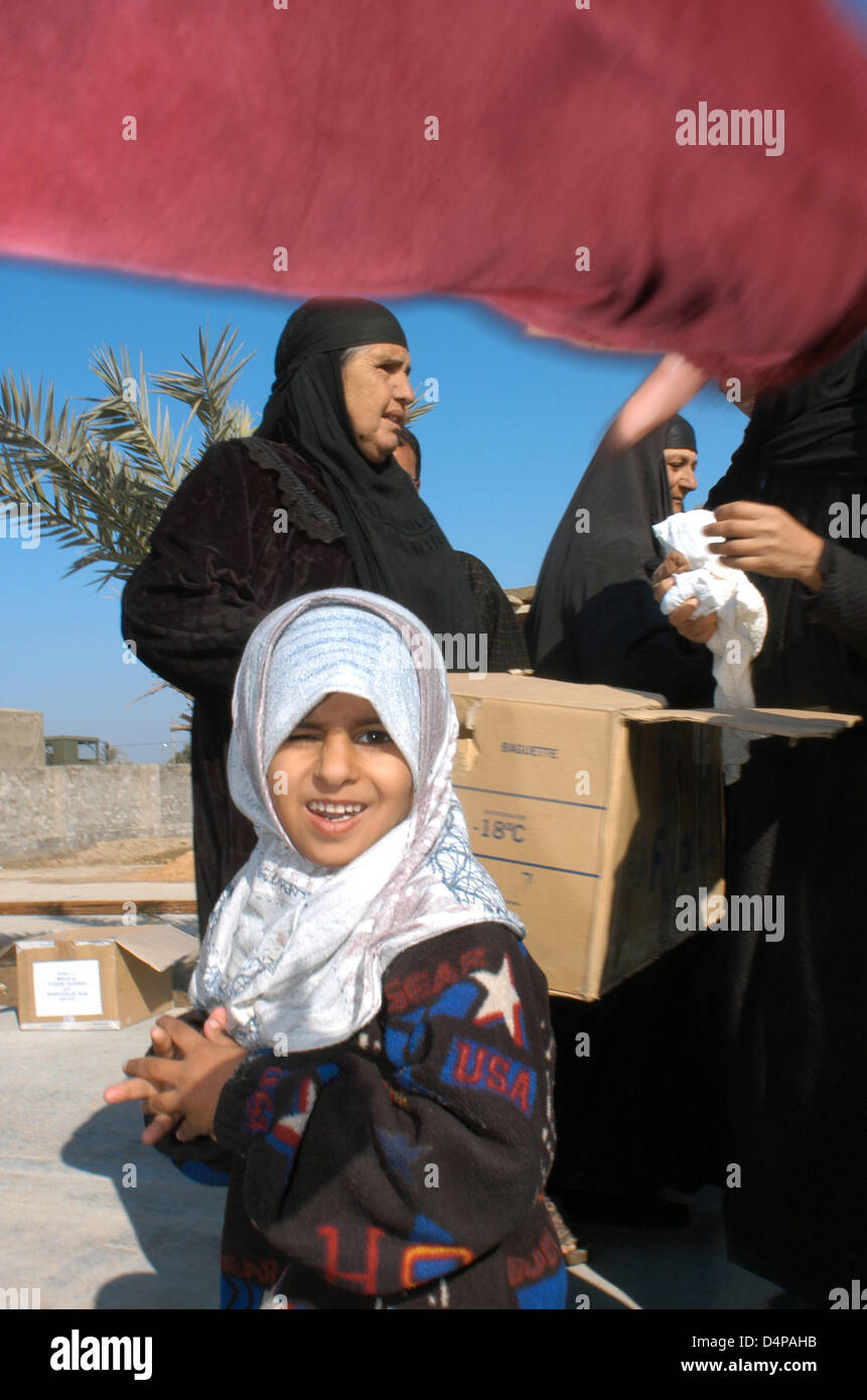 They get several boxes of humanitarian aid. While mothers are distributed warm clothes, children play around. Any clothing is welcome, although bearing the emblem of the people who murdered their family and friends. Stock Photo