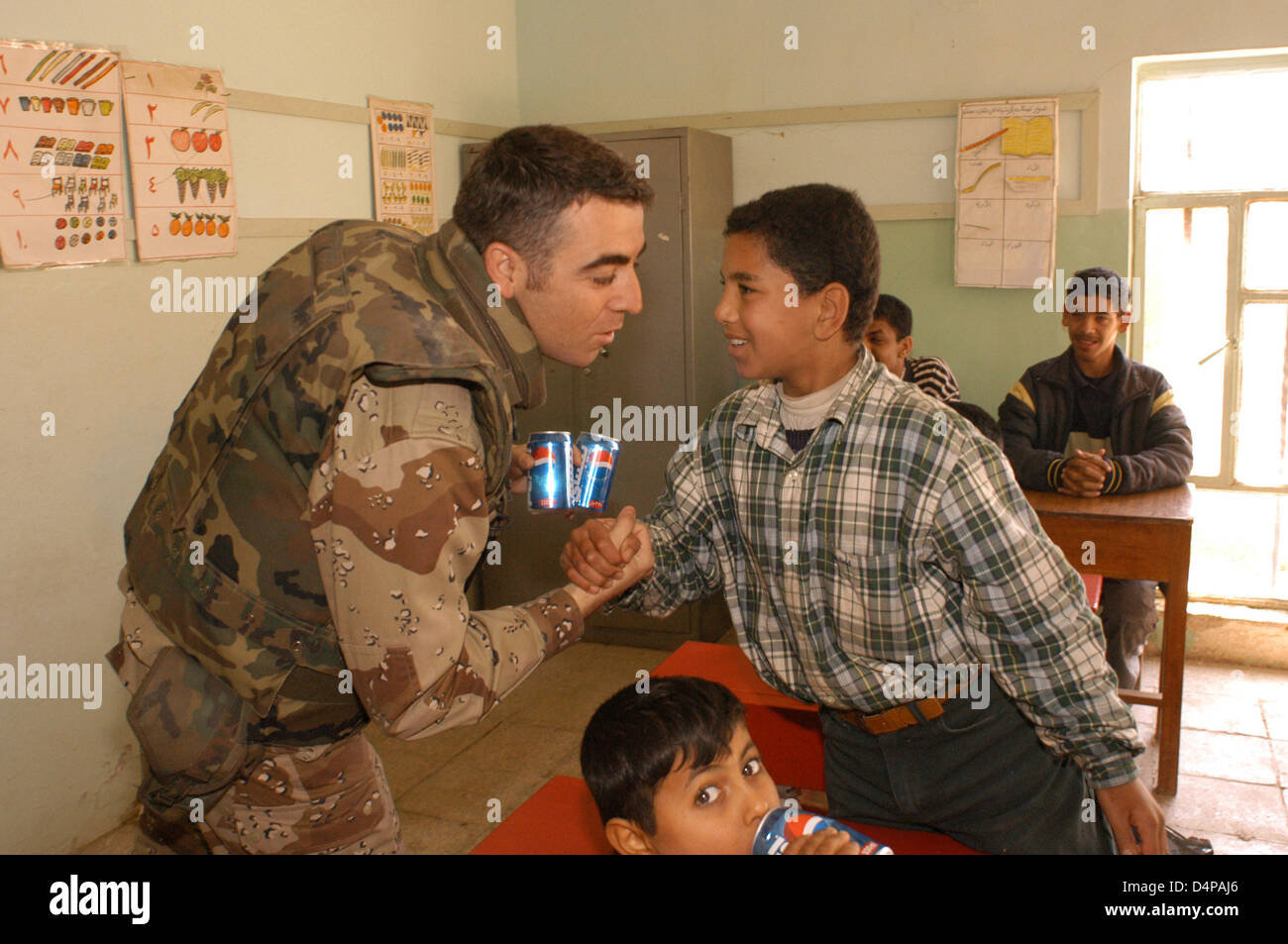 Soldier greets a boy in a school in Diwaniyah in December 2003. Stock Photo