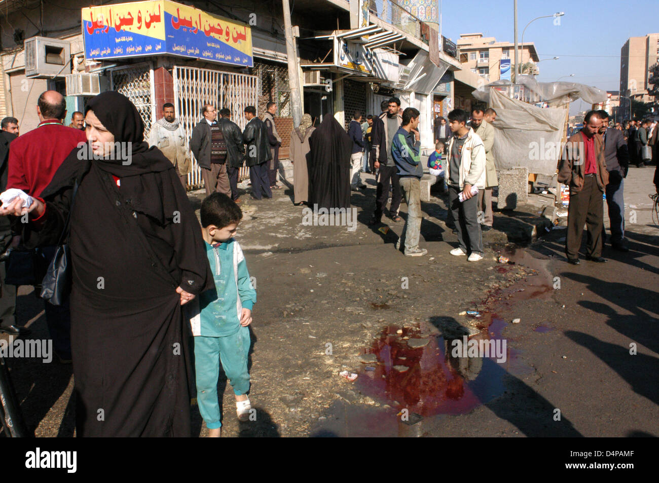 Attack against the U.S. occupation troops in the Baghdad neighborhood of Kerrada, causing serious damage to the local population. The attack killed an Iraqi and another merchant, 37, was injured. People passing by, including children, watching a big bloodb Stock Photo