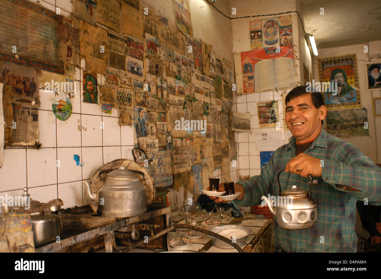 Tea Shop in Diwaniyah. Among the religious symbols and soccer players share the spotlight on the wall of the kitchen. Stock Photo