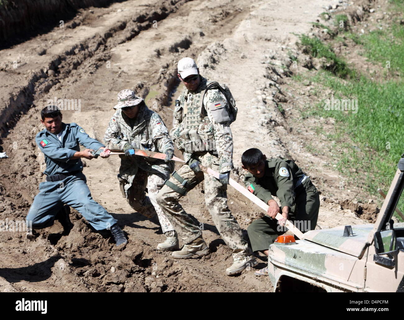 Afghan policemen and German Bundeswehr soldiers try to pull a vehicle out of the mud in the province Badakhshan, Afghanistan, 26 May 2009. Photo: Marcel Mettelsiefen Stock Photo