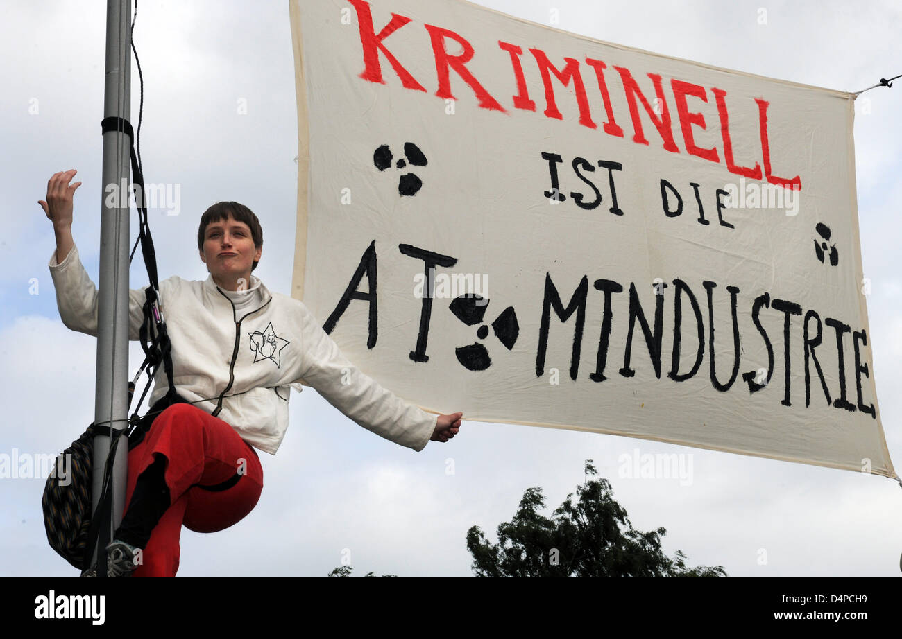 French climbing activist Cecile Lecomte hangs on a flagpole in front of the Local Court in Steinfurt, Germany, 04 June 2009. She and another woman fixed a large poster to the flagpole which reads ?The atomic industry is the criminal?. The 27-year-old has to face a charge after she let herself down on a rope over a railway line and thereby forced a transport with nulear waste to a s Stock Photo