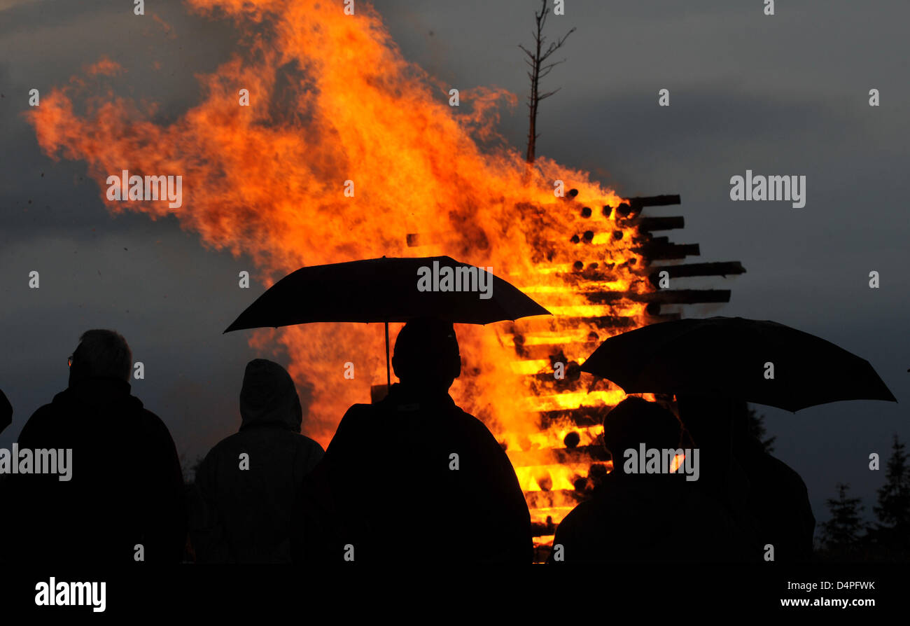 People with umbrellas watch the solstice fire on Kandel, Germany, 20 June 2009. Traditionally the local Black Forest club organises soltice fires to celebrate the shortest night of the year. Photo: Patrick Seeger Stock Photo