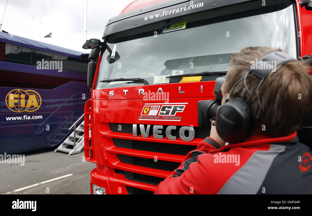 A cameraman films the FIA motorhome and a Ferrari truck in the paddock at Silverstone race track
