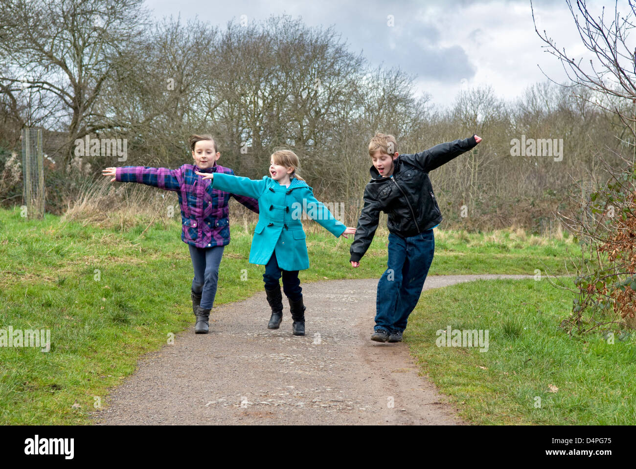 Children running making aeroplane (or airplane) shapes and having fun in park Stock Photo
