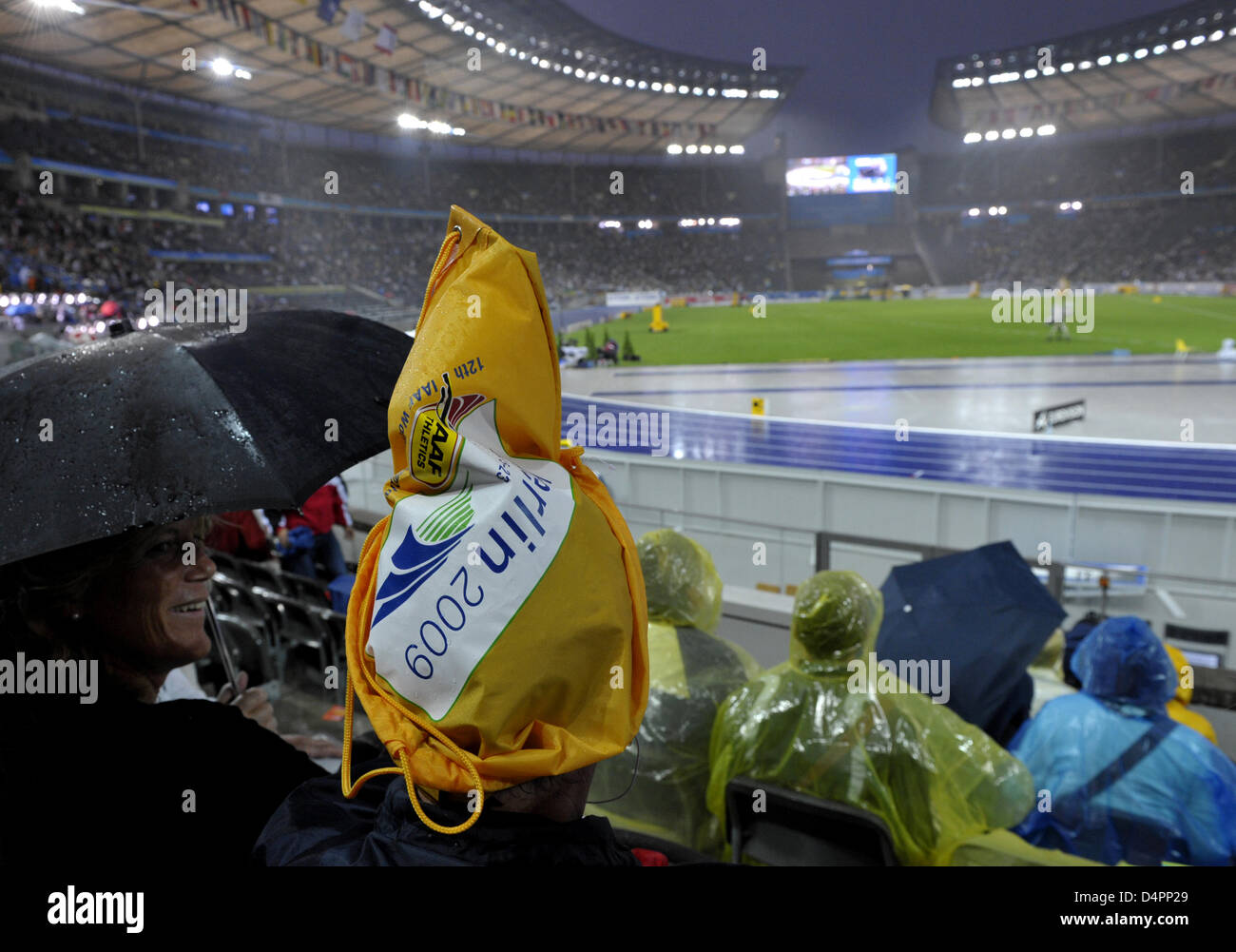 Spectators try to protect themselves from the rain during a delay of the competitions due to