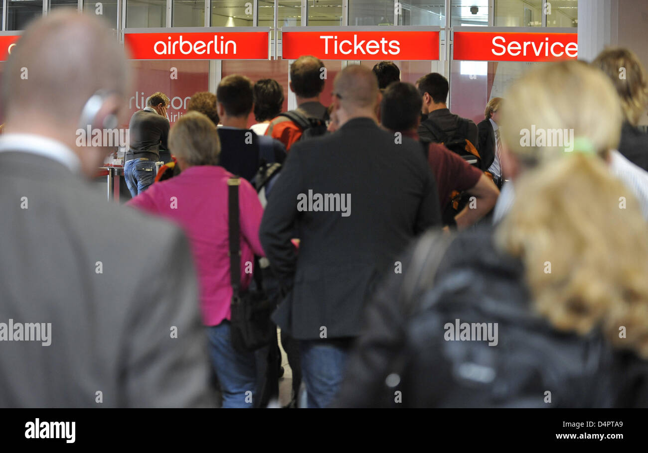Travellers stand in front of a service counter of airline Air Berlin at