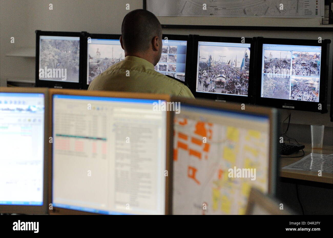A police officer works in front of computer screens showing pictures ...