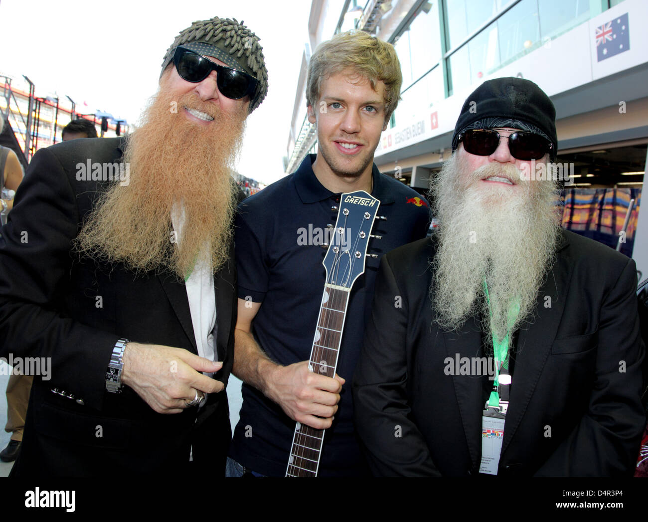 The members of ZZ Top, Dusty Hill (R) and Billy Gibbons (L), pose with  German Formula One driver Sebastian Vettel of Red Bull in the paddock at  Marina Bay Street Circuit in