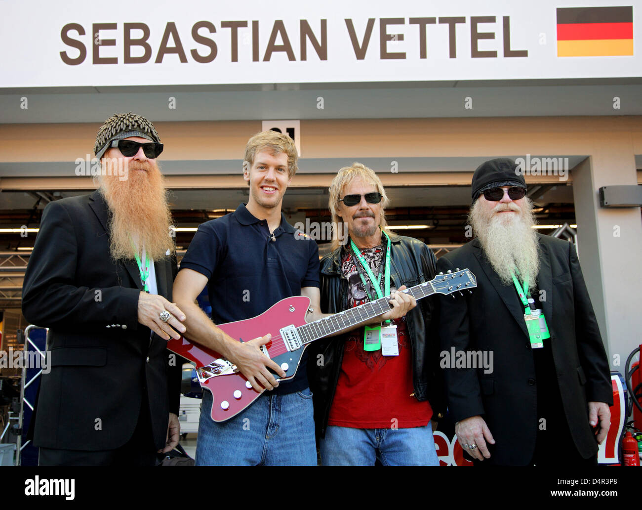 The members of ZZ Top, Billy Gibbons (L-R), Frank Beard and Dusty Hill, pose with German Formula One Sebastian Vettel (2-L) of Red Bull in the paddock at Marina Bay Street