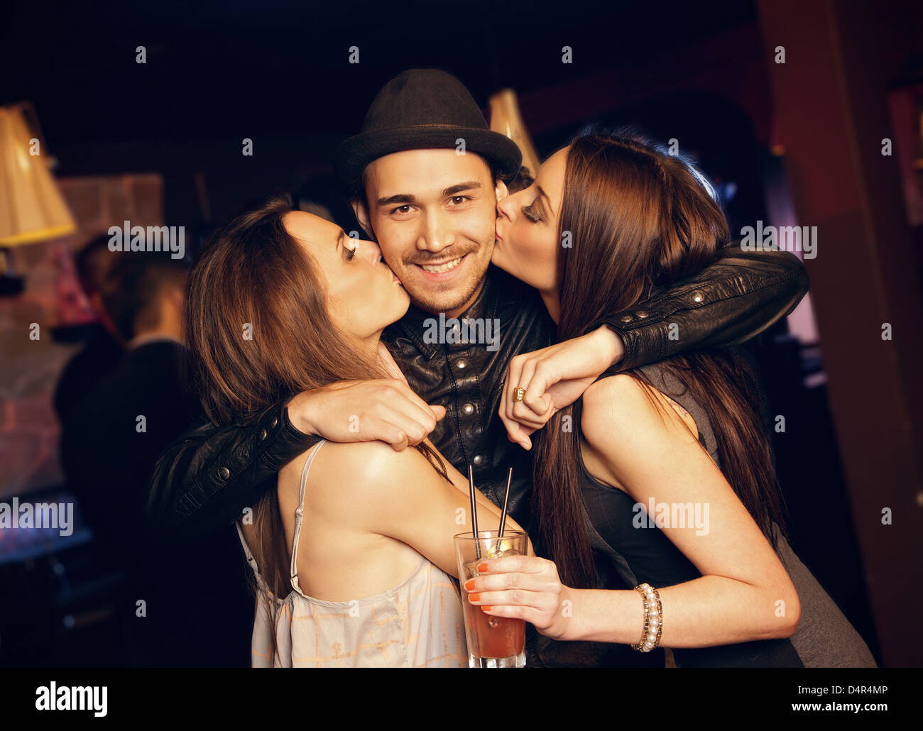 Guy gets a friendly kiss on the cheek by attractive party girls Stock Photo