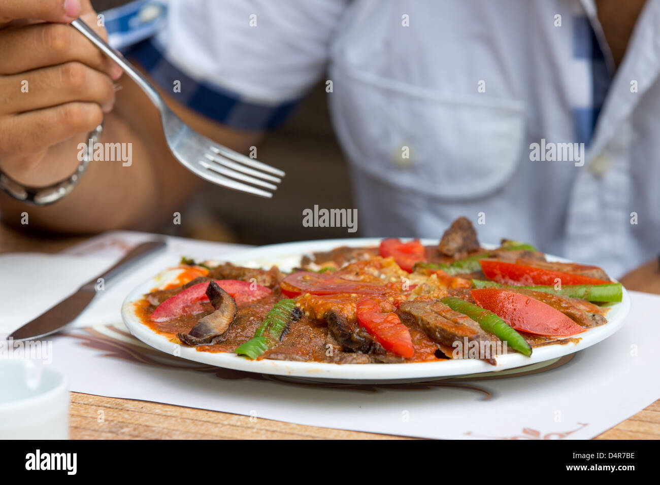 Getting ready to eat Turkish Iskender Doner, garnished with beef stripes, sliced tomatoes and peppers. Stock Photo