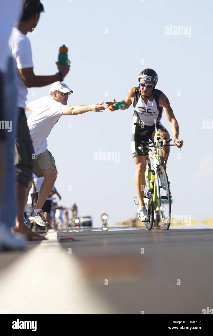 Australian triathlete Matt White takes a bottle of water while he