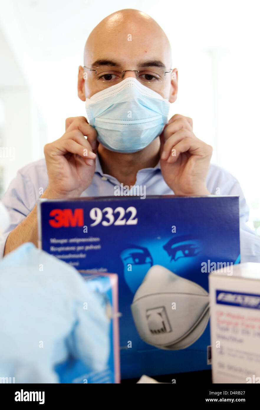 An employee of Deutsche Telekom tries on a face mask from the care package for sales representatives in Bonn, Germany, 30 July 2009. The company wants to protect itself and its employees from swine flu by the care package, hand desinfection and a flyer on pandemics. Photo: Oliver Berg Stock Photo