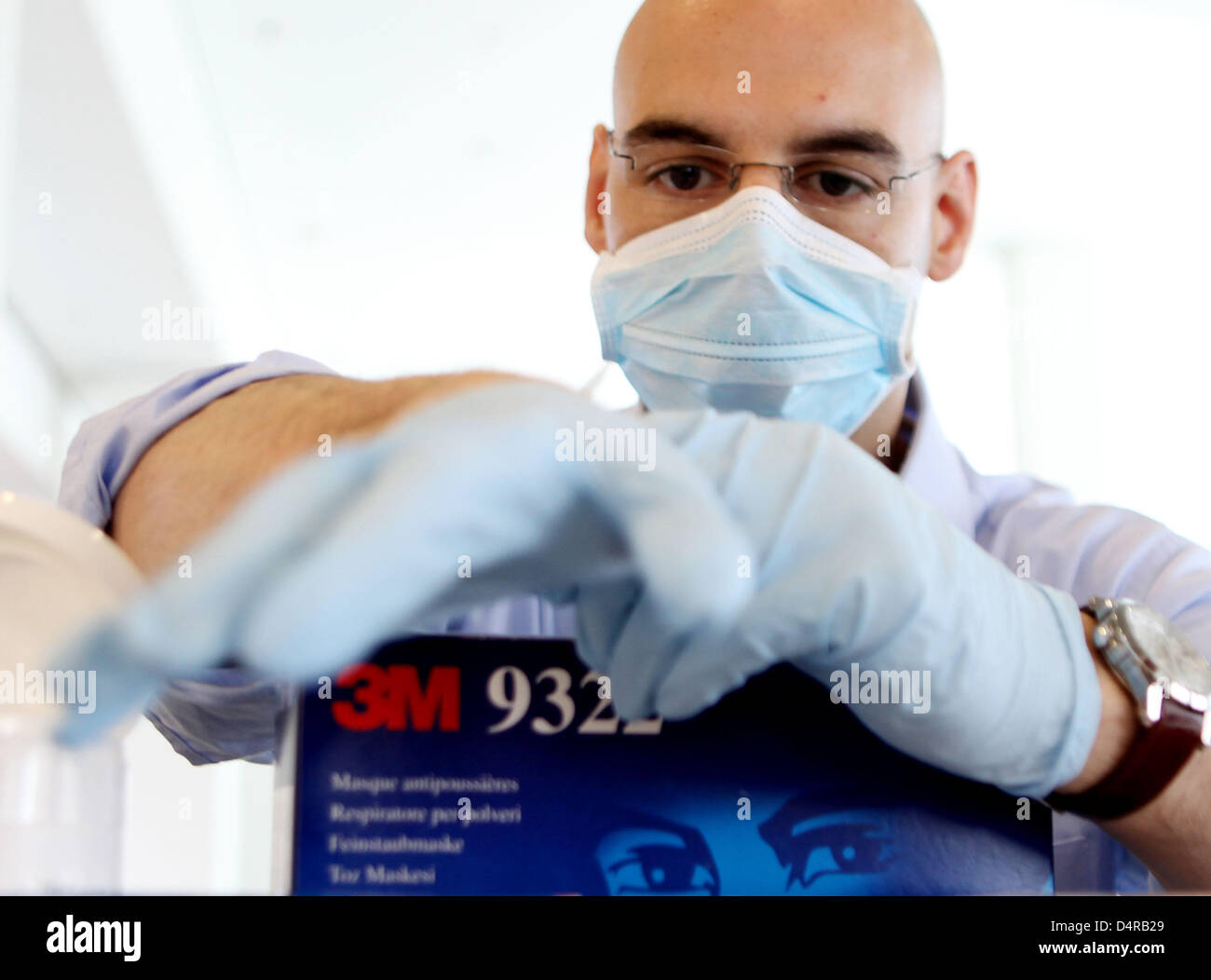 An employee of Deutsche Telekom tries on a face mask and rubber gloves from the care package for sales representatives in Bonn, Germany, 30 July 2009. The company wants to protect itself and its employees from swine flu by the care package, hand desinfection and a flyer on pandemics. Photo: Oliver Berg Stock Photo