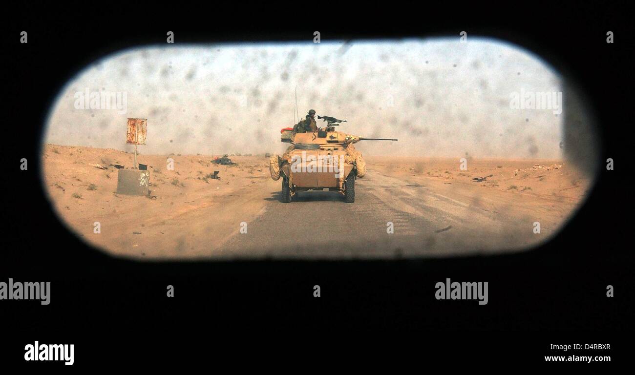 View through a window: US marines of the 3rd Light Armored Reconnaissance Batallion (3rd LAR) secure a road with their reconnaissance vehicle, on 24 March 2003, near Nasiriya in southern Iraq. Stock Photo