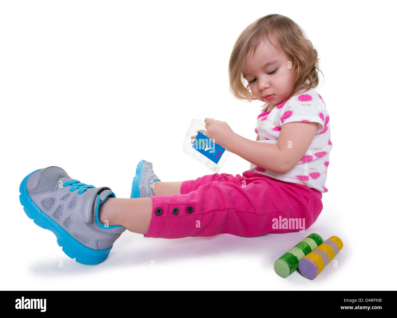 Toddler girl with colorful chalks in her hands getting ready for activity time, isolated on white. Stock Photo
