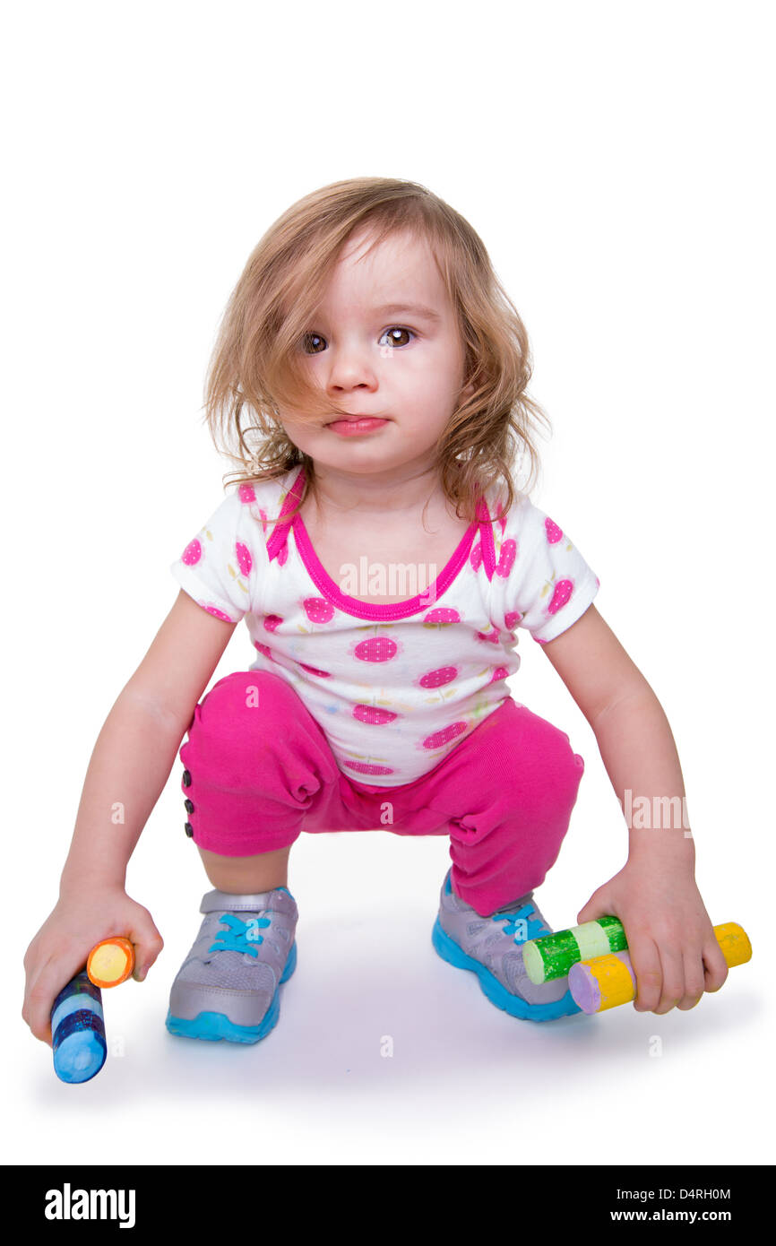 Toddler girl with colorful crayons in her hands getting ready for activity time, looking at camera. Isolated on white. Stock Photo