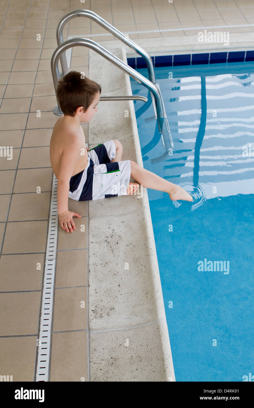 Cautious boy checking the pool water before he enters. Stock Photo
