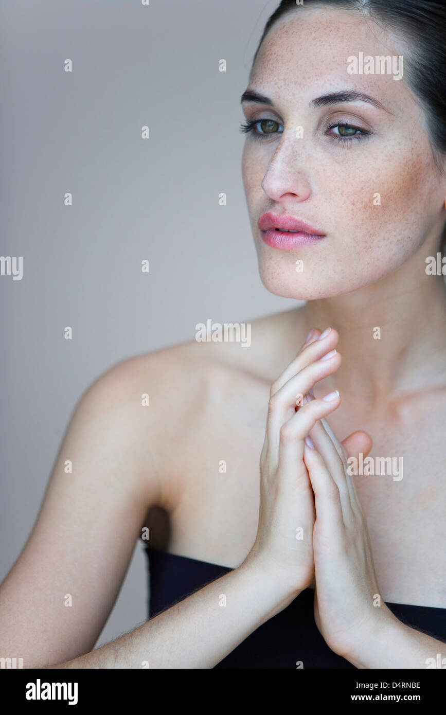 Young woman with hands clasped in front of chest, portrait Stock Photo
