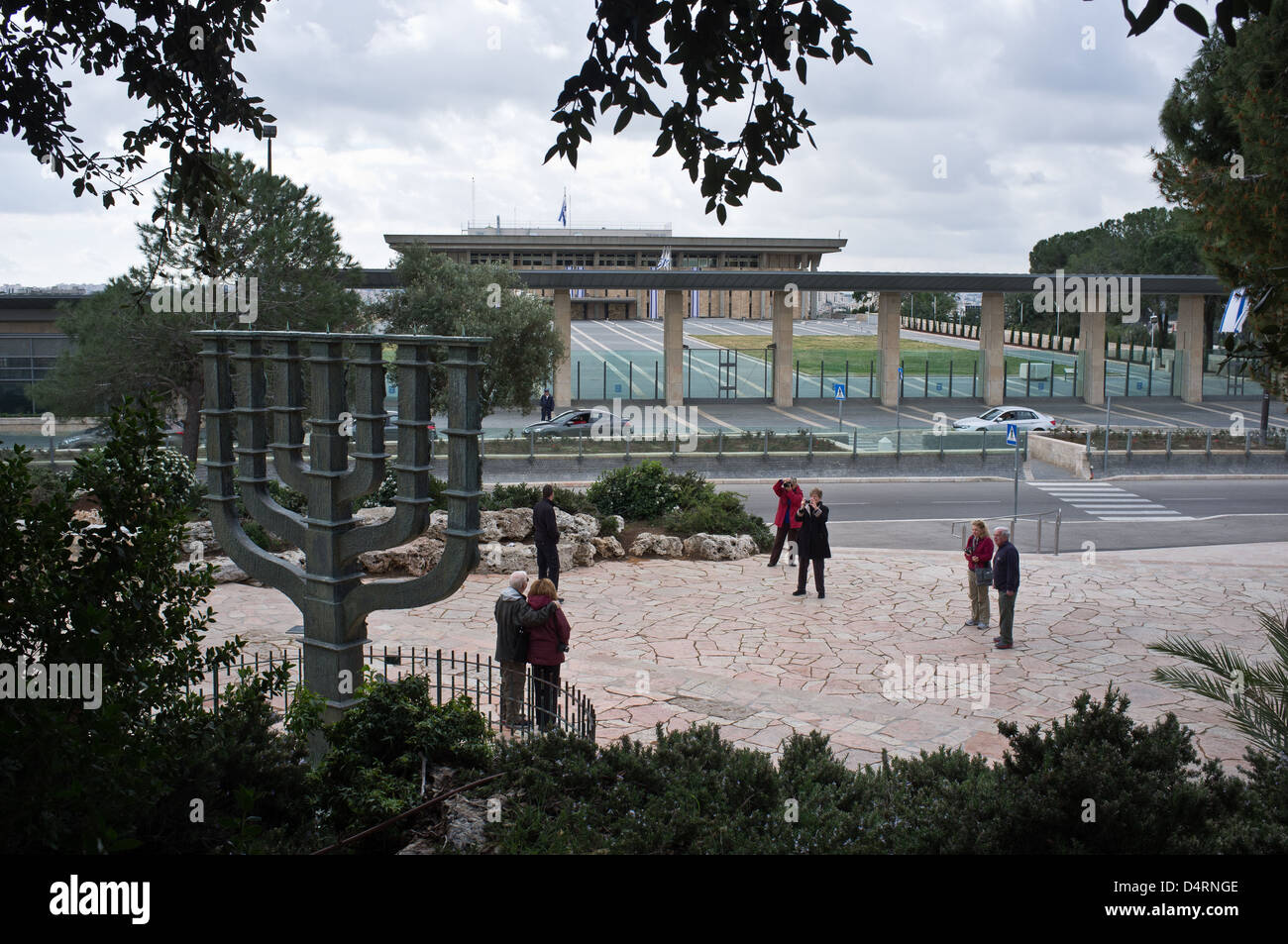 Tourists pose for photographs at a menorah on display opposite the Israeli Parliament Building in Jerusalem Stock Photo